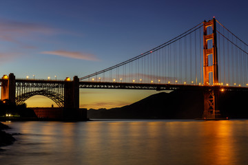 Fototapeta na wymiar Twilight lights over the Golden Gate Bridge as seen near Fort Point Historic Site. San Francisco, California, USA.