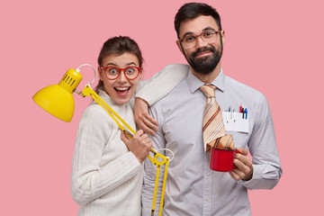 Smiling joyful young woman and man nerds stand closely to each other, collaborate for preparing and...