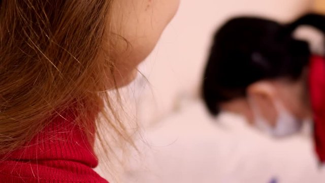 slow motion blond girl in sweater smiles sitting at table master fills up papers after belly piercing in beauty parlour 