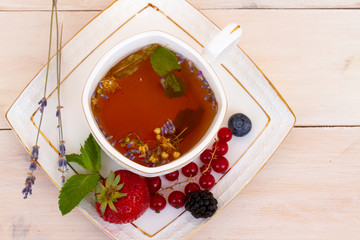 Herbal tea with lavender and mint, fresh strawberries, blackberries and blueberries on a white wooden table. Berry tea with fresh strawberry, blackberry. top veiw
