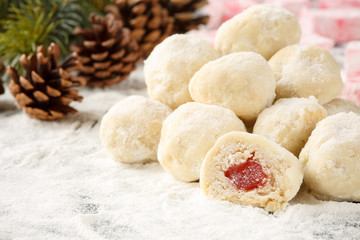 Pile of whole and half sliced traditional bulgarian homemade cookies with turkish delight filling, called Lokumki, decorated with snow like podered sugar, pine cones and twigs