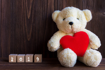 2019 Cute teddy bear with red heart on old wood, copy space.  Merry Christmas and Happy New Year Concept.