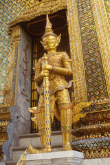 Fototapeta premium Golden statue of ancient guard in Wat Phra Keao, The Grand Palace, Bangkok, Thailand. Outdoors, copy space.
