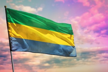 Fluttering Gabon flag on colorful cloudy sky background. Prosperity concept.