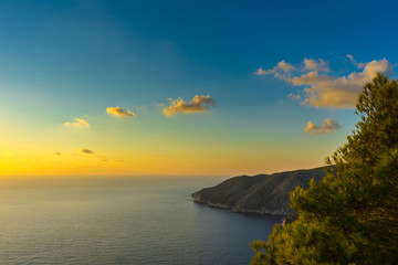 Greece, Zakynthos, Romantic orange sunset over endless blue ocean and beautiful cliffs at the coast