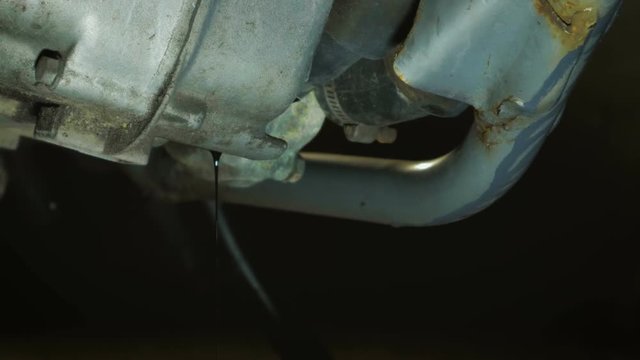 Close-up of the motorcycle engine crankcase with merging old waste oil into a plastic canister