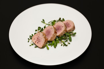 Pork tenderloin with fresh herbs on white plate