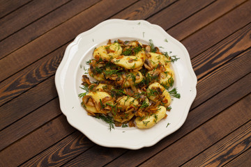 Gnocchi with a mushroom sauce and fresh herbs on a white plate, on a wood background