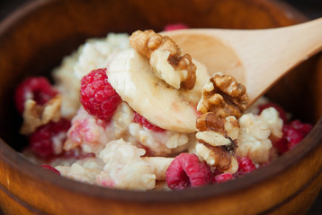 Delicious oatmeal with banana raspberries and walnuts. Close-up