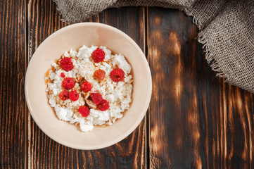 Natural cottage cheese with raspberries and honey on a wooden vintage table. Top view.