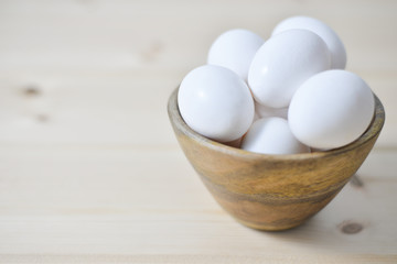 white eggs on wooden plate on wooden background , copy space 