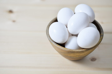 white eggs on wooden plate on wooden background , copy space 