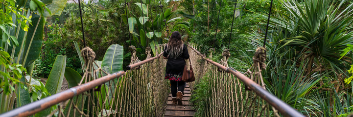 Woman walking over a suspension bridge in the jungle