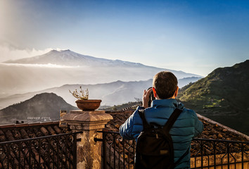 Woman photographing etna volcano during eruption