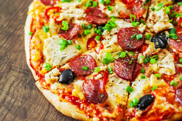 Pizza with Chicken meat, Mozzarella cheese, pepperoni, tomato, olive, salami. Italian pizza on wooden background