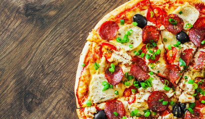 Pizza with Chicken meat, Mozzarella cheese, pepperoni, tomato, olive, salami. Italian pizza on wooden background