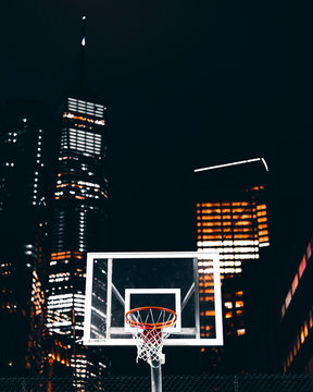 Basketball Rim In Front Of Skyscrapers, Night Lights