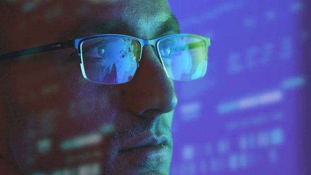 The man in glasses looking to the display on the hologram background