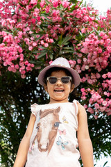 Fototapeta premium Beautiful girl with glasses and hat in front of flowers