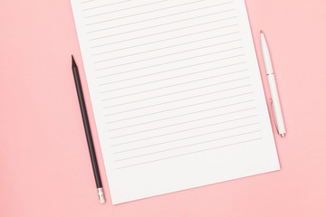 Blank page in a line with black pencil and white pen. Plans and goals for the year. Freelancer workplace concept. Top view with copy space for input the text. Flat lay, colored pink background.