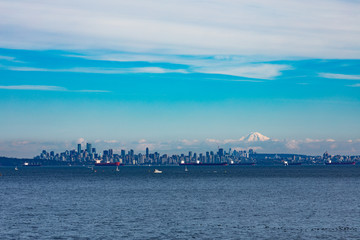 Vancouver City at the Western Canadian Pacific Ocean coast with oil tankers anchored in harbor and Mount Baker in the far distance shadowing the cityscape skyline, Biritish Columbia, BC, Canada