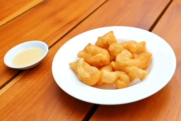 Deep-fried dough stick with sweetened condensed milk on wooden background. 