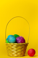 colorful, hand-painted, pastel Easter eggs in a basket on a bright, yellow, spring background