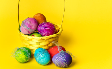 colorful, hand-painted, pastel Easter eggs in a basket on a bright, yellow, spring background