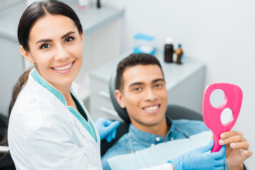 selective focus of attractive female dentist standing near african american patient