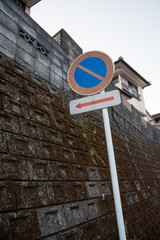 Wide of no parking sign next to a wall downtown during sunset. Nobeoka, Japan. Vertical orientation. Travel and urban lifestyle.