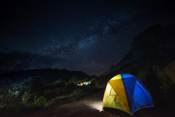 Glowing tent in the mountains under a starry sky