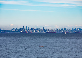 Fototapeta na wymiar Vancouver City at the Western Canadian Pacific Ocean coast with oil tankers anchored in harbor and Mount Baker in the far distance shadowing the cityscape skyline, Biritish Columbia, BC, Canada