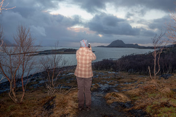 Fototapeta na wymiar Woman walks along the seafront in Brønnøy municipality, Nordland county