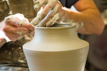 Artist potter in the workshop sculpting ceramic vase. Hands closeup. Small artistic craftsmen business concept. 