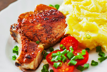 Grilled pork loin meat with mashed potatoes and salad in white plate