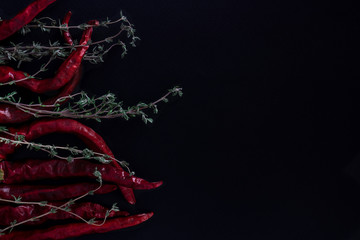 Pepper and thyme on a black background. Copy space.