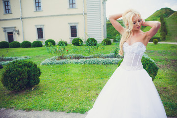Fototapeta premium Beautiful blonde princess bride posing near old medieval castle