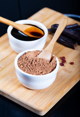 Carob pods and carob powder over wooden background 