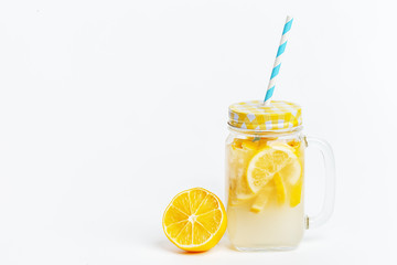 A jar of homemade lemonade and lemons on a white background.