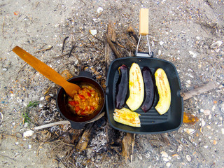 Cooking grilled eggplants in a cast-iron pan grill at the stake. Food tourists.
