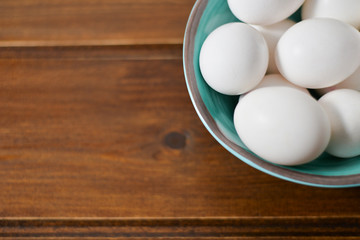 white eggs on wooden plate on wooden background , copy space 