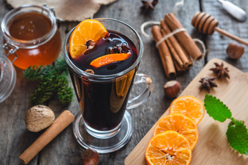 Hot mulled wine with orange, cinnamon, honey and anise on wooden background.