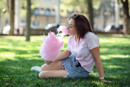 a girl on a kirtag with cotton candy. fun and joy of fair.girl greedily eating sweets on the background of the Park