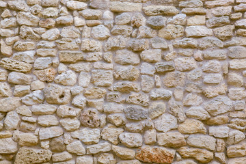 Stone wall of natural stones in different sizes. The facade of the old house.