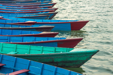 empty old wooden blue red green boats on the water stand in a row