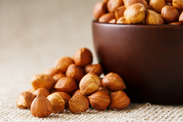 Peeled hazelnuts in a wooden, dark brown cup on a burlap cloth. Super Food, Raw.