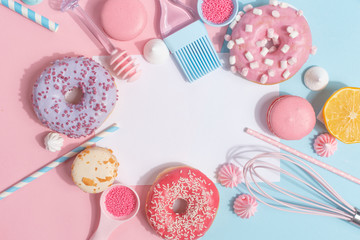 Kitchen utensils and tools, pastries and sweets on a pink and blue background. Top view. Copy space.