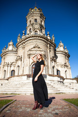 Fototapeta premium Young woman in black dress on the background of the church