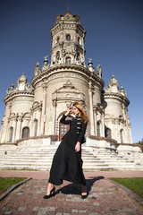 Fototapeta na wymiar Young woman in black dress on the background of the church