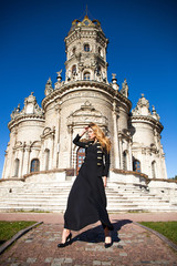 Fototapeta premium Young woman in black dress on the background of the church